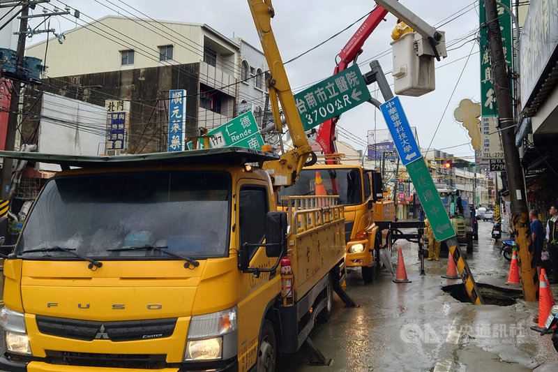 台南市仁德區中正路一處路面，15日疑似因自來水管線破裂，地基掏空造成電桿及號誌桿傾斜。中央社記者楊思瑞攝　115年6月15日