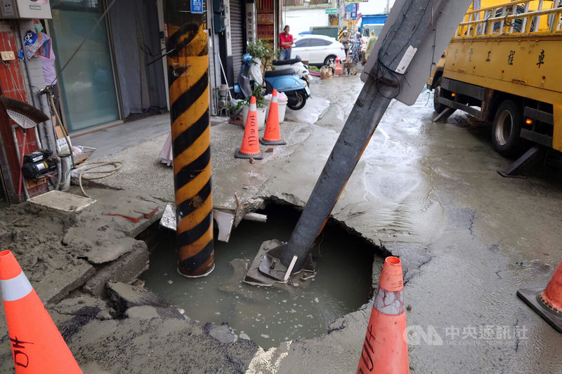 台南市仁德區中正路一處路面15日疑似因自來水管線破裂，地基掏空造成路面下陷，出現坑洞積水，電桿及號誌桿傾斜。中央社記者楊思瑞攝　115年6月15日