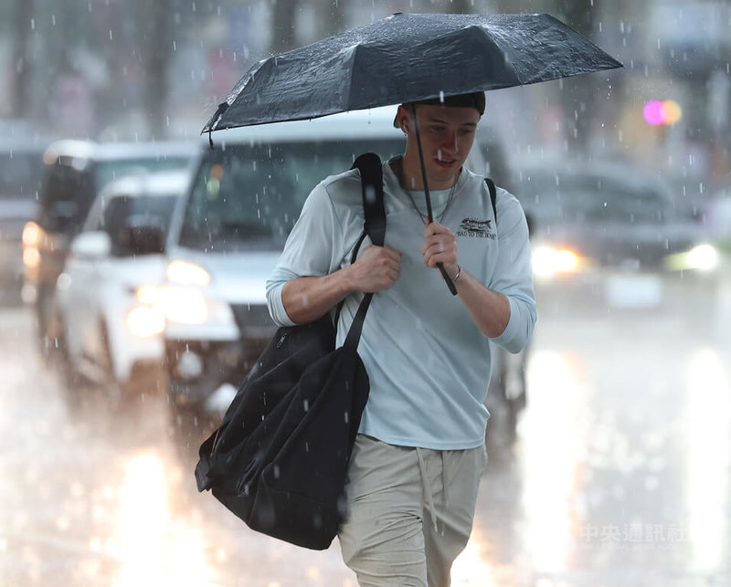 中央氣象署17日下午針對大台北等12縣市發布大雨特報，午後對流雲系發展旺盛，易有短延時強降雨，中部以北防局部大雨發生。圖為台北市信義區民眾撐傘遮擋雨勢。中央社記者張新偉攝　115年6月17日