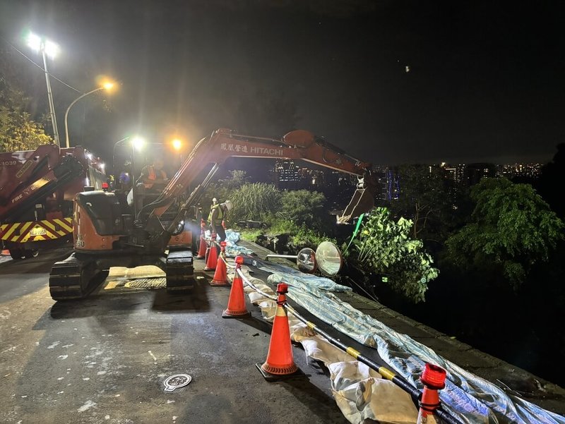 新北市新店區涵煙翠社區前路段受大雨影響,18日下午發生土石崩落意外,市府緊急調度機具進場搶災,並覆蓋帆布避免邊坡持續滑落。(新北市工務局提供)中央社記者曹亞沿傳真 115年6月18日
