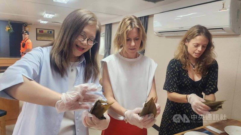 端午將至,海委會主委管碧玲(左)邀英國在台辦事處代表包瓊郁(中)登上雲林艦,管碧玲也示範折粽葉、填料及綁繩技巧,並按步驟教導包瓊郁包出人生第一顆台灣粽。中央社記者洪學廣攝 115年6月18日