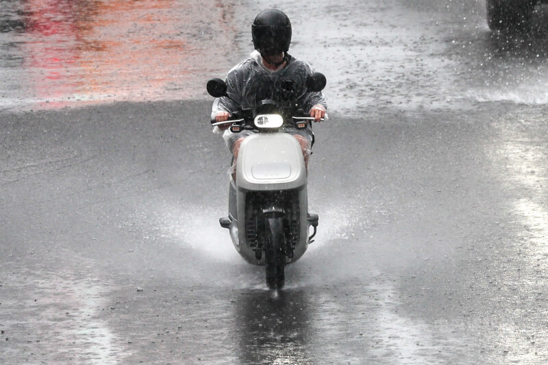 圖為新北市蘆洲區午後降下強降雨，機車騎士經過積水路段掀起水花。（中央社檔案照片）