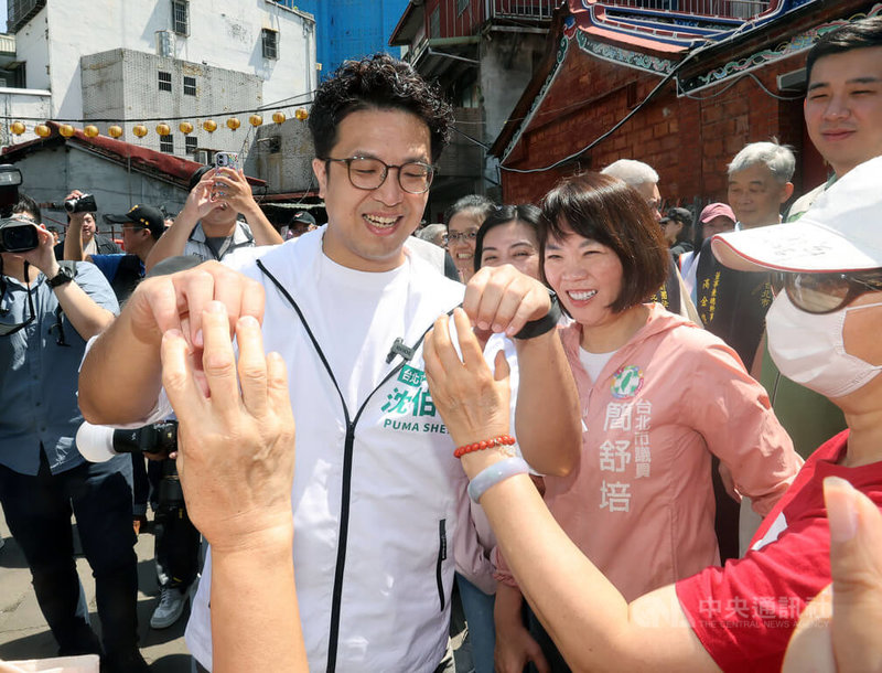 民進黨台北市長參選人沈伯洋(前左)20日上午赴景美集應廟參拜後,前往景美市場掃街,與市民朋友合比愛心互動。中央社記者郭日曉攝 115年6月20日