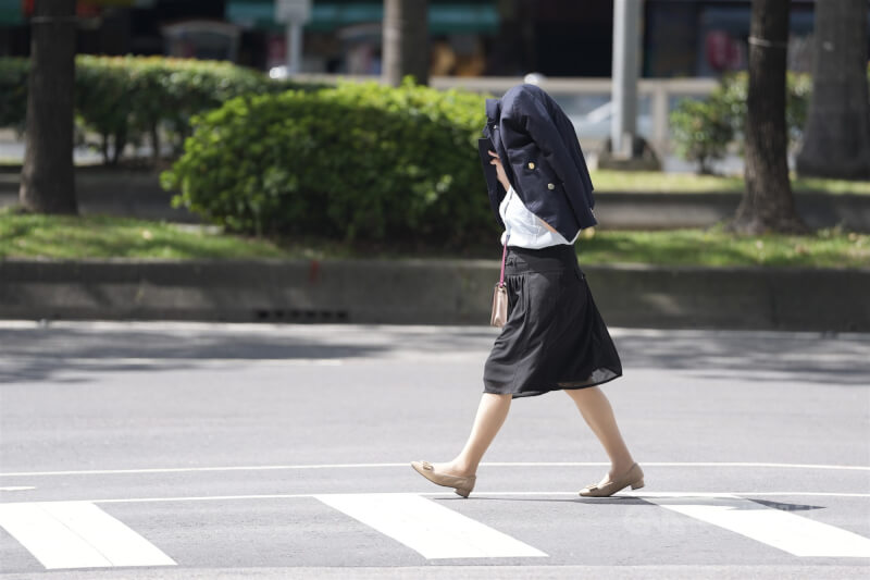 圖為台北市中正區民眾以衣物遮擋豔陽。（中央社檔案照片）