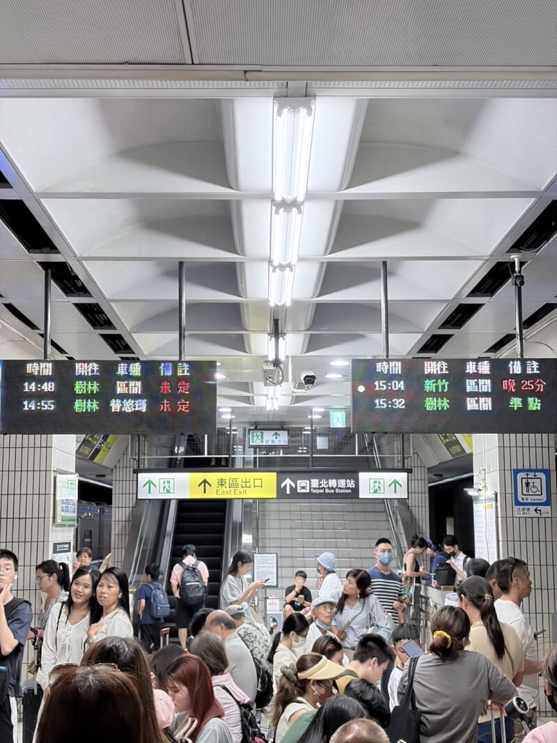 台鐵21日板橋至樹林間因軌道接縫處有高低差，目前改為單線雙向行車，台北車站月台看板備註可見發車時間「未定」資訊，許多乘客在月台候車。（讀者提供）