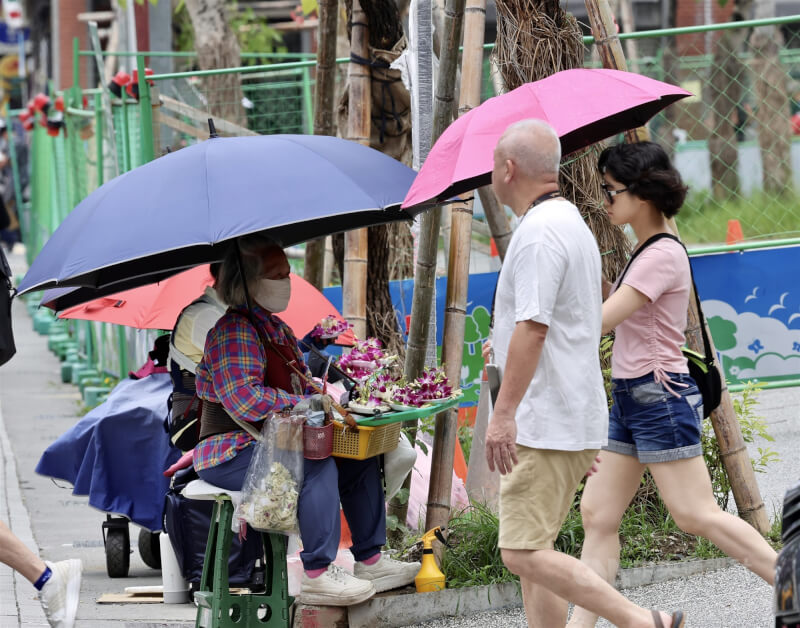 圖為北市萬華區民眾撐傘防曬。（中央社檔案照片）