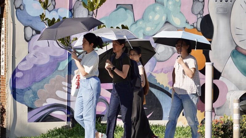 圖為在高雄駁二藝術特區旅遊民眾紛紛撐傘遮陽，躲避強烈日照。（中央社檔案照片）
