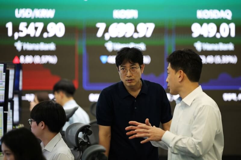 韓股23日在科技股拖累下暴跌，觸發熔斷機制，一度暫停交易，終場重挫10%。圖為韓國交易員在寫有韓國股市資訊的螢幕前交談。（路透社）