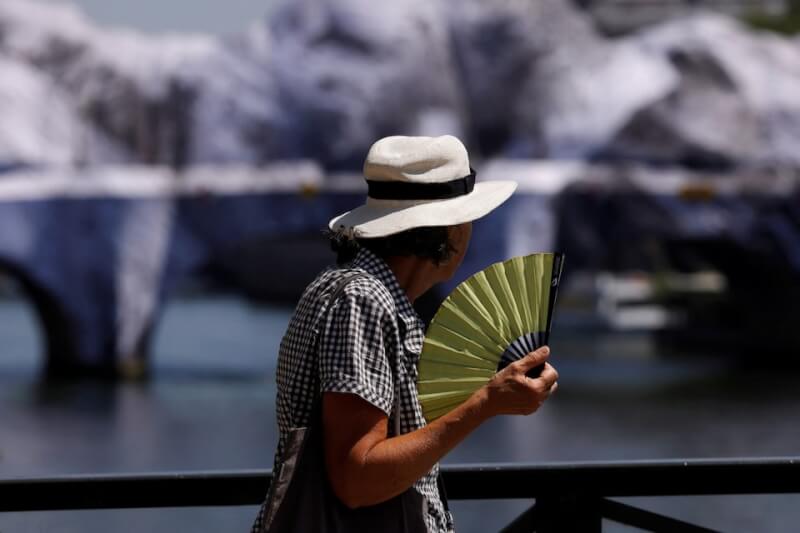 法國遭熱浪侵襲，行人手持扇子搧風。（路透社）