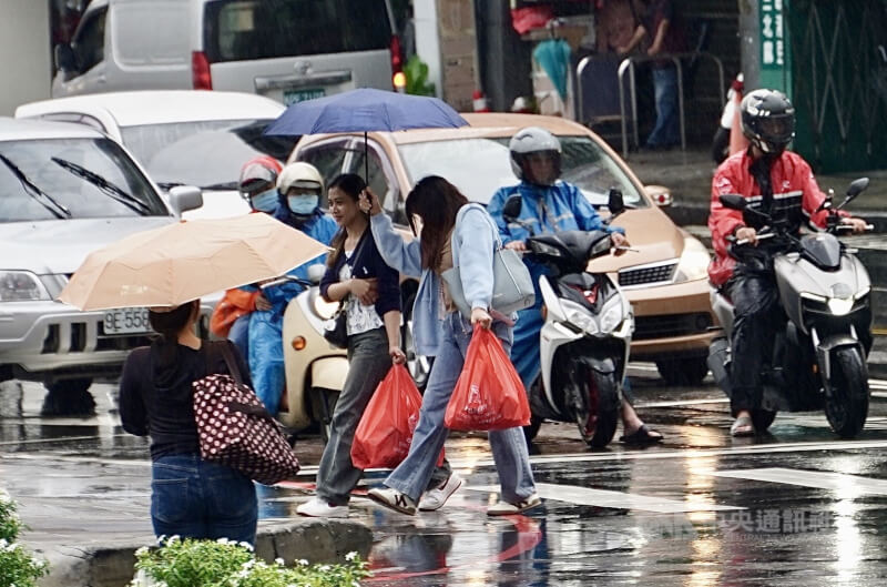 圖為高雄市三民區路上行人撐傘過馬路。（中央社檔案照片）