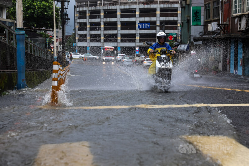 氣象署25日上午發布豪雨特報。新北市淡水區因大雨造成路面有積淹水情形，騎士經過激起水花。 中央社記者吳家昇攝 115年6月25日