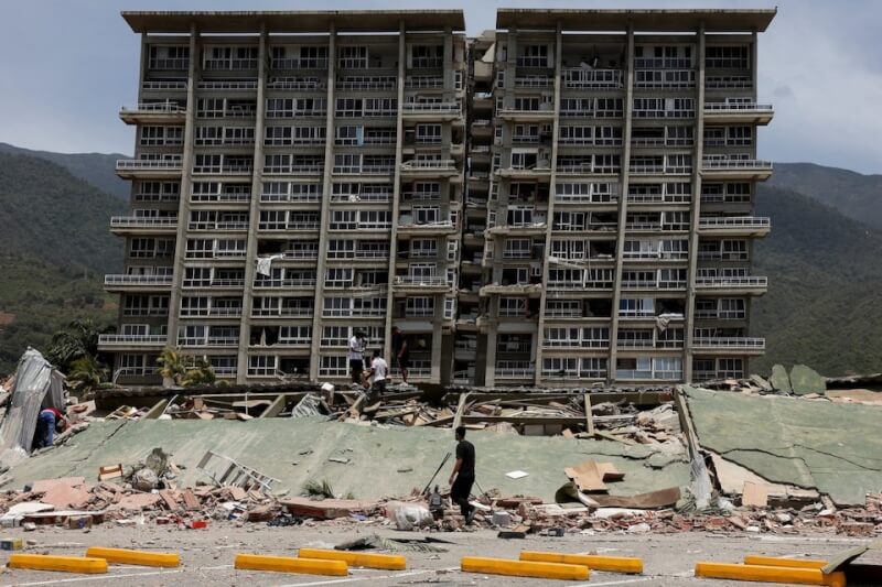 委內瑞拉遭連環強震侵襲，官方26日表示死亡人數增至589人。圖為地震後民眾查看倒塌的建築物。（路透社）