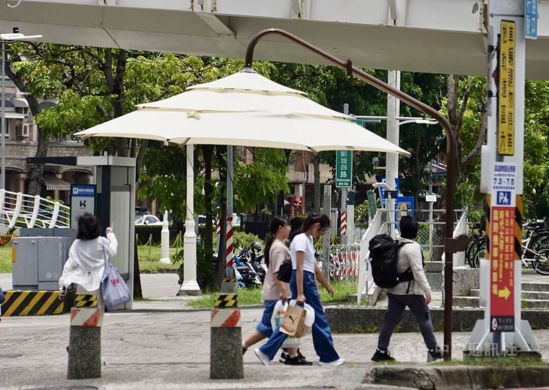 高雄天氣炎熱，市府與捷運公司試辦裝設路口手動收折遮陽傘，29日正式啟用。圖為高雄輕軌C3站與捷運站間的轉乘路口設置手動收折遮陽傘。中央社記者董俊志攝　115年6月29日