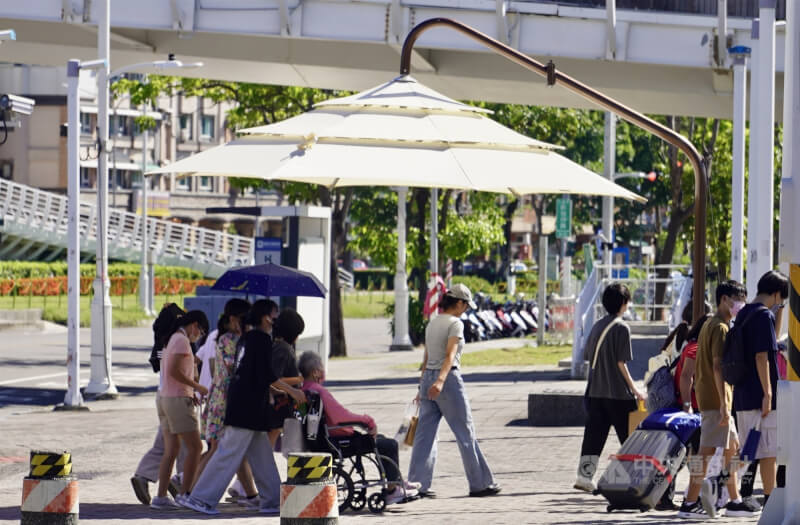 夏日酷暑難耐，高雄、新北、台北近期陸續設置行人遮陽傘，其中高雄採用手動裝置，需人工開啟。圖為高雄輕軌車站與捷運站間路口設置的遮陽傘。中央社記者董俊志攝　115年7月2日