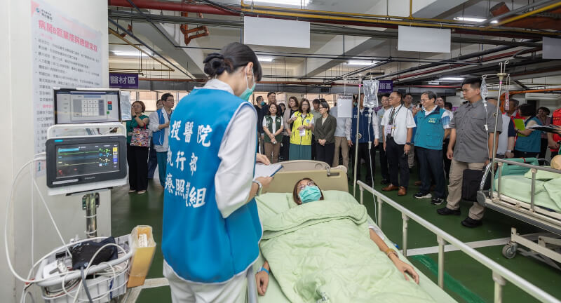 副總統蕭美琴(後中灰衣者)聽取衛福部次長林靜儀(後中黃衣者)說明醫院執行演練情況。(圖取自總統府flickr)