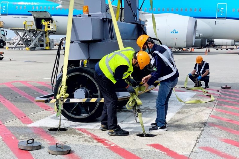 颱風巴威逼近,桃園國際機場10日下午針對未使用的D6候機室A380客機專用空橋進行預防性綁橋固定作業,工作人員先將空橋收回至停止區並下降,以輪擋固定行駛輪,再以綁帶將空橋固定於地面錨錠。中央社記者吳睿騏攝 115年7月10日