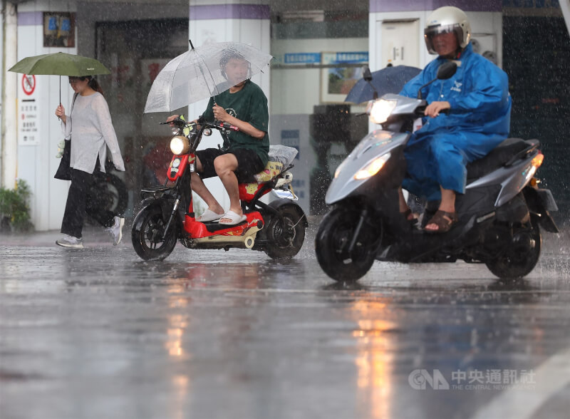 圖為台北市信義區民眾撐傘騎車過馬路。（中央社檔案照片）