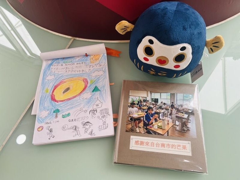 台南芒果正值產季，台南市長黃偉哲致贈日本山口縣防府市愛文芒果，讓學童在營養午餐享用，學童們也繪製畫冊表達感謝。（台南市政府提供）中央社記者張榮祥台南傳真  115年7月15日