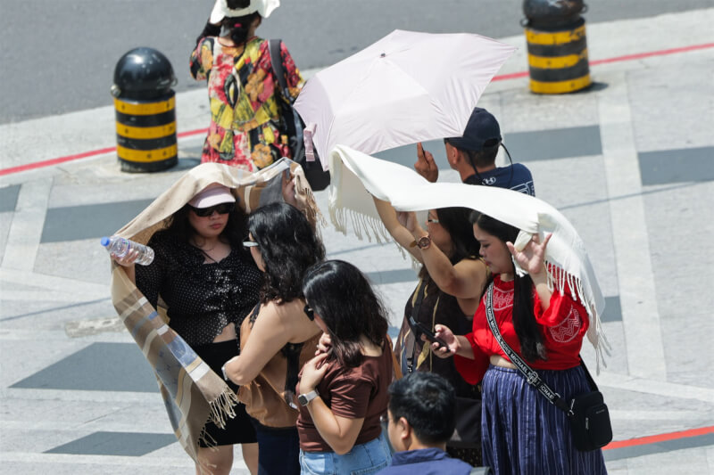 圖為觀光客中午在台北市信義區等待過馬路，拿圍巾遮陽防曬。（中央社檔案照片）