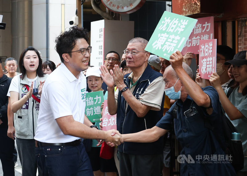 民進黨台北市長參選人沈伯洋(前左)18日上午前往直興市場拜票,獲得不少民眾歡迎,現場「凍蒜」聲不斷。中央社記者謝佳璋攝 115年7月18日