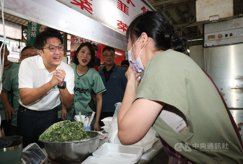 民進黨台北市長參選人沈伯洋(左)18日上午前往直興市場拜票,向攤商拱手致意懇請支持。中央社記者謝佳璋攝 115年7月18日