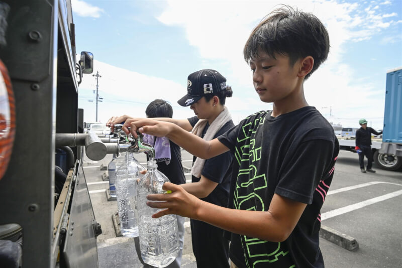 日本熊本縣部分地區在28日地震後仍有斷水、斷電，民眾排隊取水。（共同社）