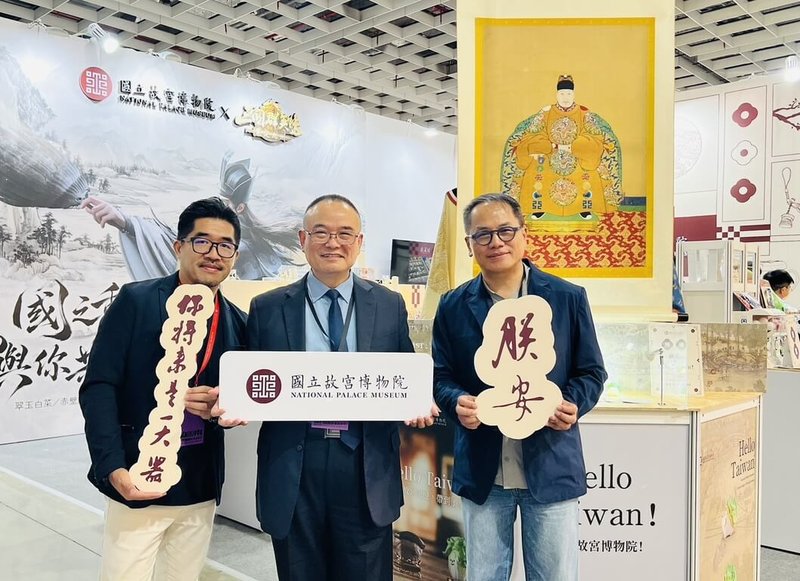 國立故宮博物院在台灣文博會商展準備「觀汝似有瘋症」系列貼紙中的金句打卡板，國家文化藝術基金會董事長彭俊亨（右）7日參觀故宮文博會攤位，與院長蕭宗煌（中）合影留念。（故宮提供）中央社記者王寶兒傳真　115年8月7日