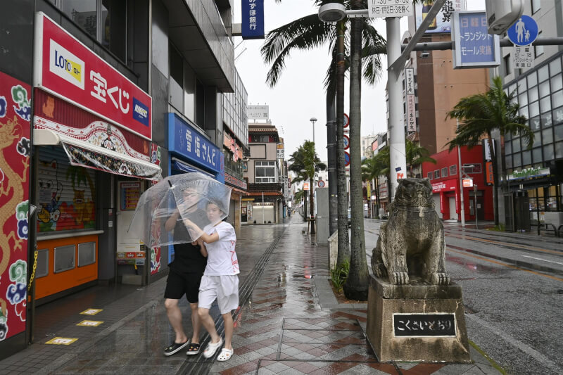 颱風白海豚8日侵襲日本沖繩縣，圖為那霸市街頭撐傘行走的民眾。（共同社）