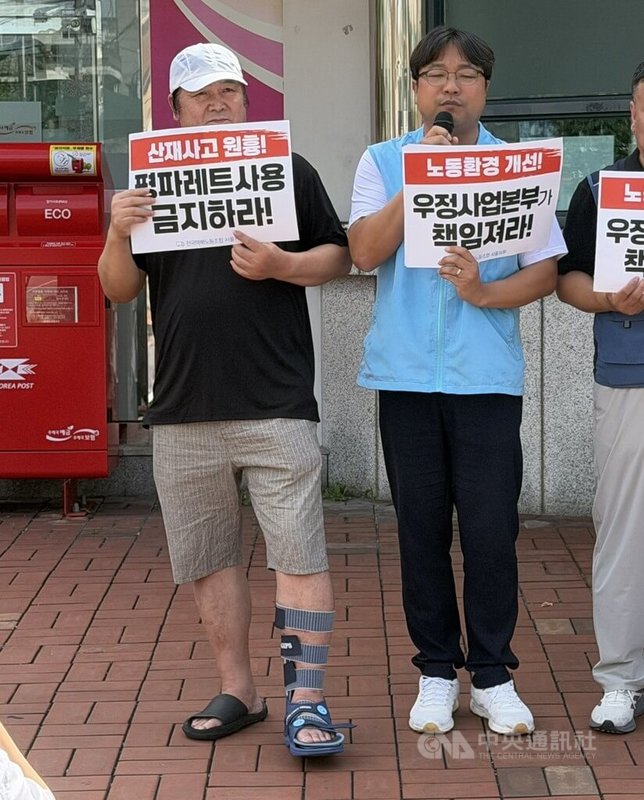 韓國民主勞總全國宅配工會10日在東首爾郵件集中局前示威,在分類作業中腳背骨折的快遞員朴泰宇(左)10日帶傷出席記者會,腳部仍穿著護具。中央社實習記者呂世婷首爾攝 115年8月10日