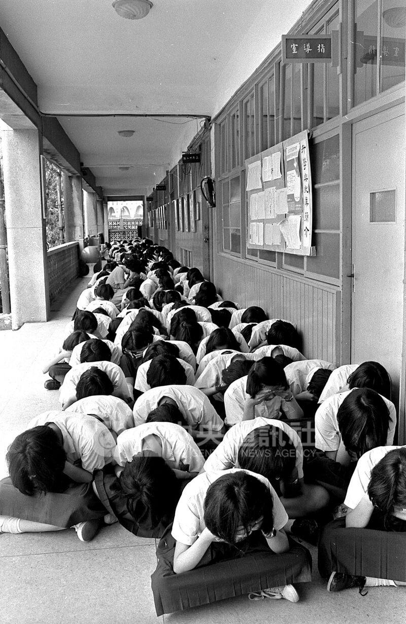 1980年6月10日台北市「萬安3號」防空演習，警報發放後，學生們在教室外抱頭蹲伏。（中央社檔案照片）