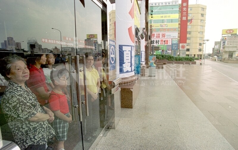 2000年8月15日萬安演習警報發布後，台北車站附近民眾配合就地掩蔽，在大樓內望著空蕩蕩街道。（中央社檔案照片）