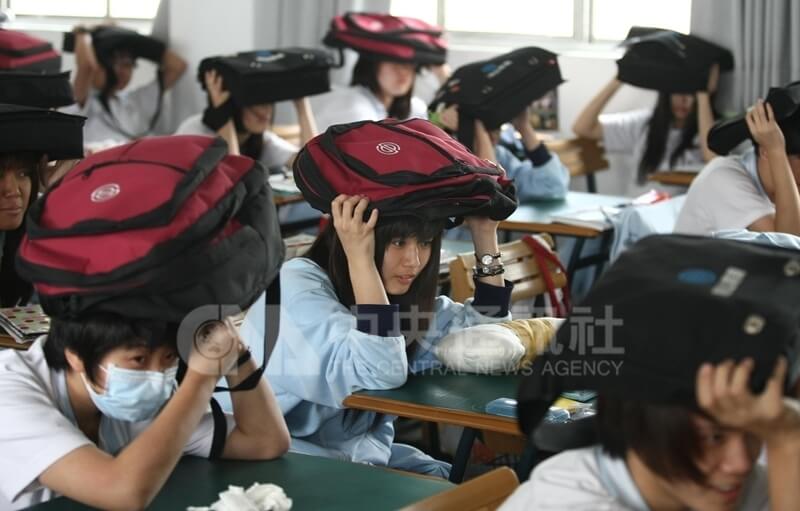 2011年5月18日防空演習警報響起，台北市松山家商學生在老師的指揮下，把書包舉在頭上掩護。（中央社檔案照片）