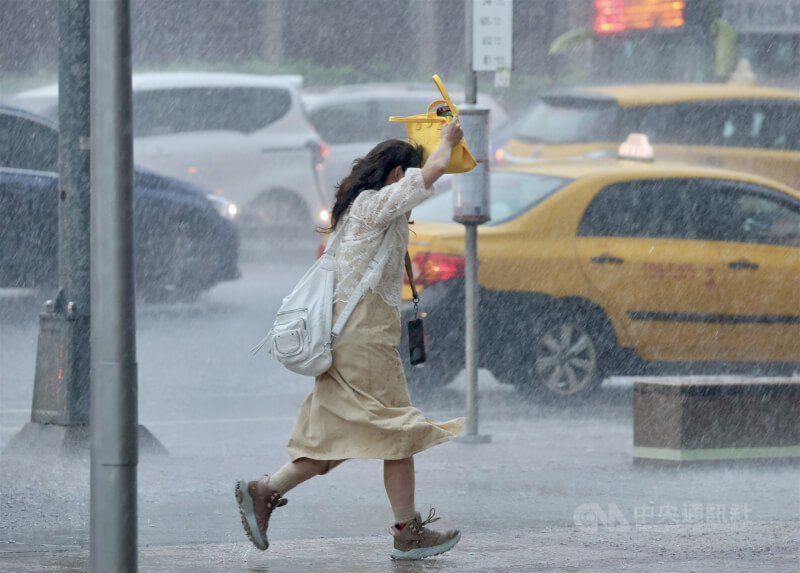 圖為台北市台北車站附近民眾只能以提包遮雨。（中央社檔案照片）