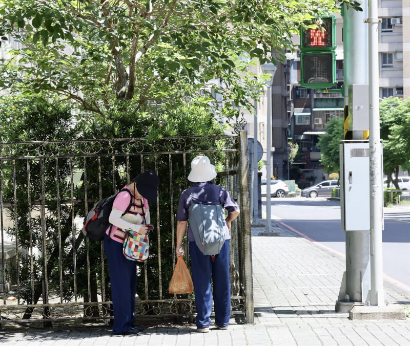 圖為台北市萬華區民眾在樹蔭下等紅綠燈。（中央社檔案照片）