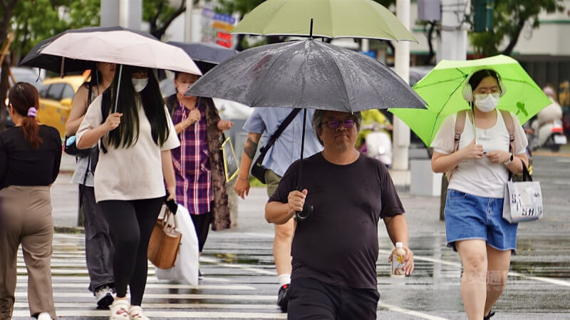 圖為高雄市區民眾在雨天撐傘過馬路。（中央社檔案照片）
