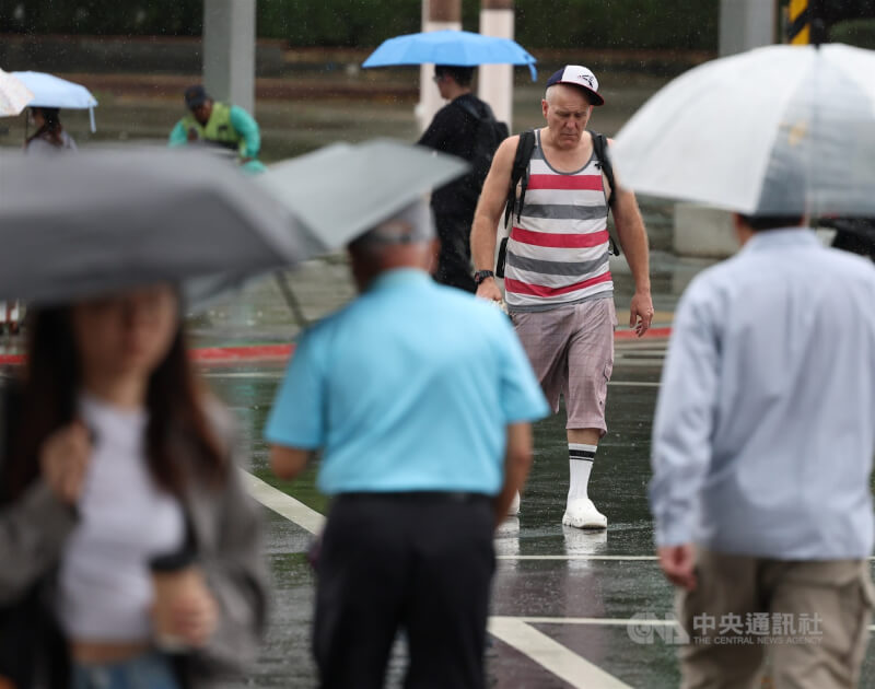 圖為北市信義區民眾在雨中快步過馬路。（中央社檔案照片）
