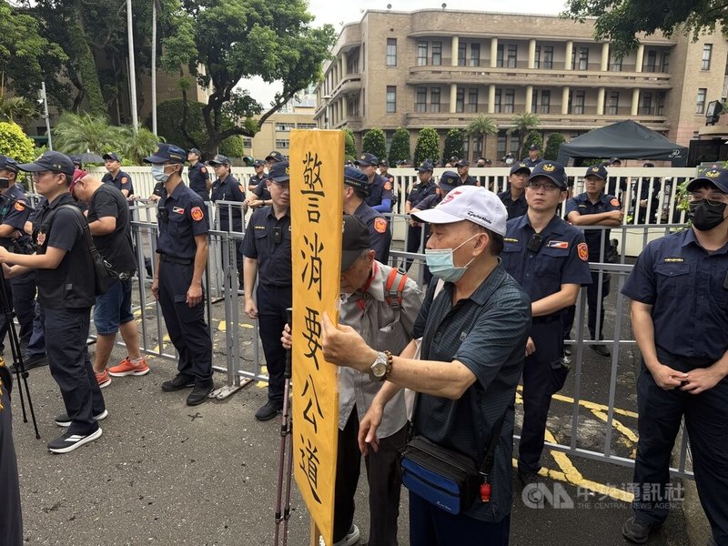 立法院在民國114年三讀修正提升軍人待遇及退休警消所得替代率，法案經總統公布後，行政院以相關修法涉及權力分立及預算編列權爭議為由聲請釋憲，未將相關經費編入預算。退休警消20日帶著抗議標語前往行政院，要求政府補足相關待遇與保障。中央社記者徐肇昌攝　115年8月20日