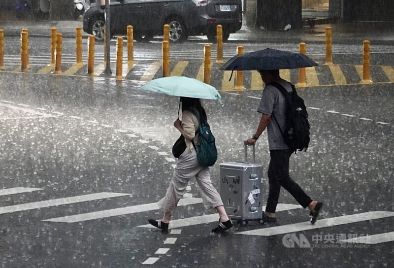 高雄市街頭行人撐著傘快步過馬路。（中央社檔案照片）