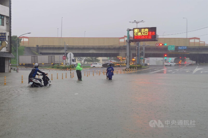 國道1號台南仁德交流道周邊23日清晨因雨勢出現積淹水,仁德交流道北向入口一度封閉,有機車騎士牽車勉強涉水通過積水路段。中央社記者楊思瑞攝 115年8月23日