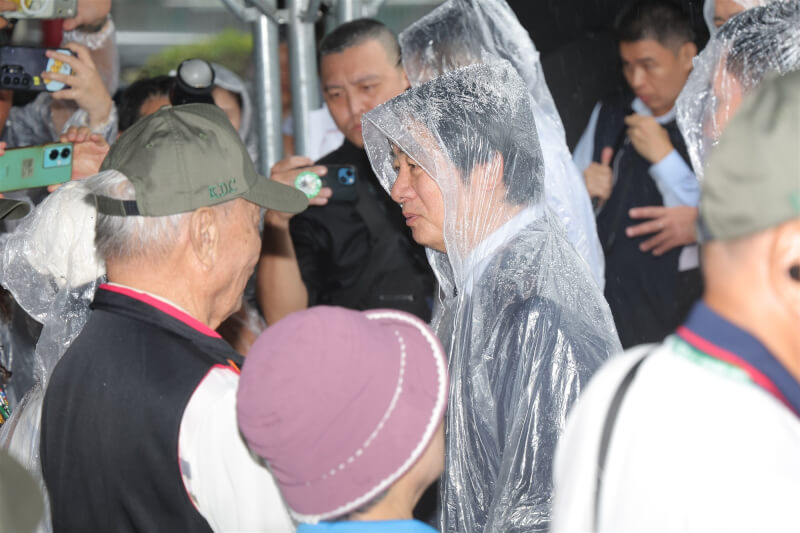 總統賴清德（前雨衣）23日赴金門太武山公墓主持「823戰役勝利68週年追悼典禮」，典禮後向823戰役陣亡烈士遺族握手致意。 中央社記者翁睿坤攝　115年8月23日