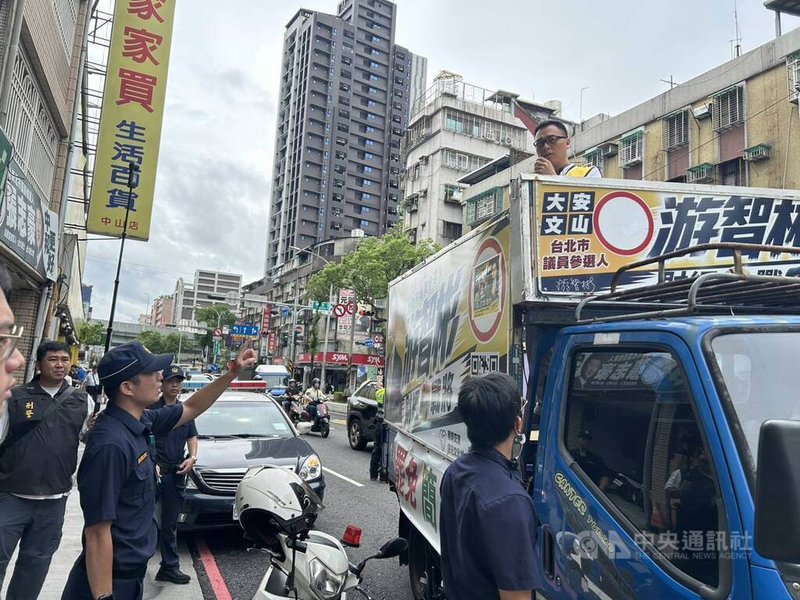 新黨台北市議員參選人游智彬（車上）25日搭著宣傳車到民進黨新北市議員參選人張志豪服務處抗議，還一度扔擲雞蛋，中和警分局獲報到場實施預防性部署與安全維護，後續並將游智彬依毀損現行犯帶回偵訊。（翻攝畫面）中央社記者曹亞沿傳真　115年8月25日
