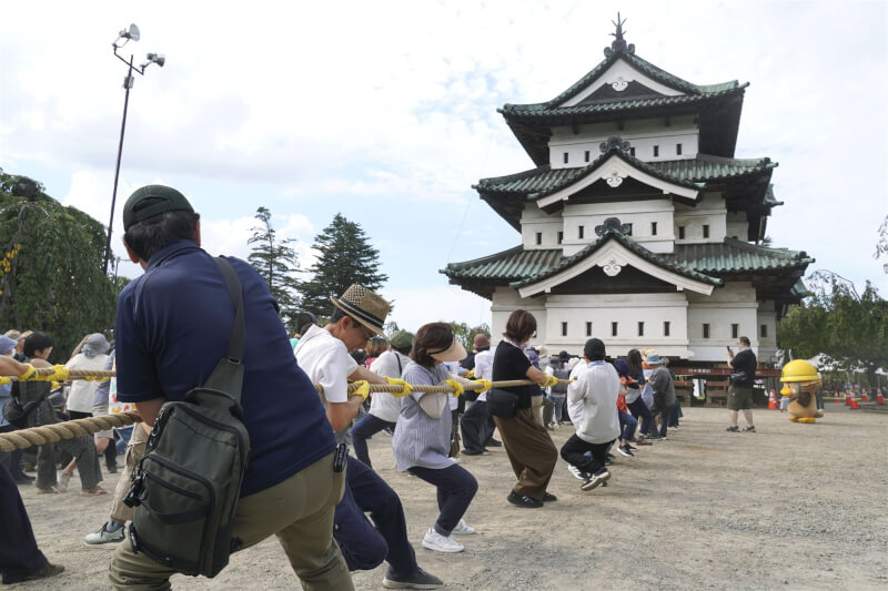 在日本東北部青森縣弘前市，民眾拉動繩索將弘前城天守閣送回原址。（共同社）