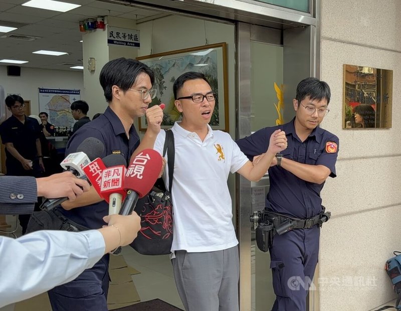 新黨台北市議員參選人游智彬（右2）25日朝民進黨新北市議員參選人張志豪服務處丟雞蛋，遭警方逮捕。游智彬在移送過程中高舉雙手、高喊自身立場。中央社記者曹亞沿攝　115年8月25日