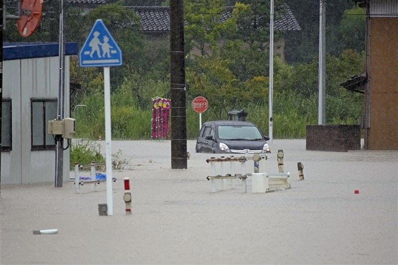 富山縣冰見市27日出現淹水，車輛泡在水中。（共同社）