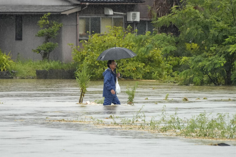 富山縣冰見市出現淹水，民眾涉水而過。（共同社）