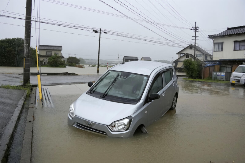 日本石川縣、富山縣27日降下大雨，富山縣冰見市出現淹水，車輛泡在水中。（共同社）