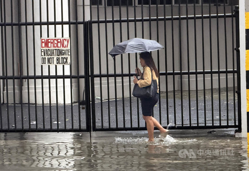 菲律賓近週接連受到颱風與西南季風影響，持續降下豪雨。圖為一名女子29日在馬尼拉市涉水而行。中央社記者林行健馬尼拉攝　115年8月29日