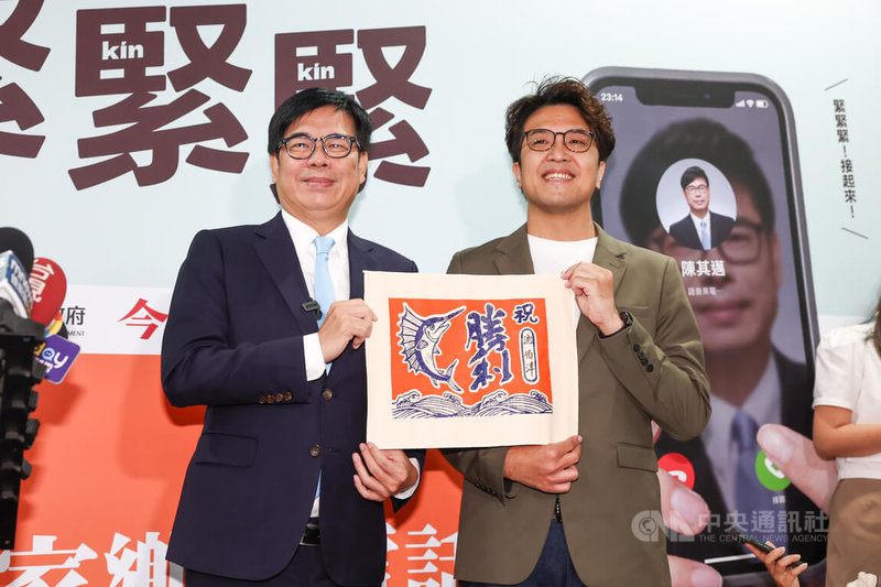 高雄市長陳其邁(左)4日在台大醫院國際會議中心舉行「高雄,緊緊緊:2314天極限轉型」新書發表會,會前受訪時特別贈送勝利旗幟給民進黨台北市長參選人沈伯洋(右),祝福選情順利。中央社記者王騰毅攝 115年9月4日