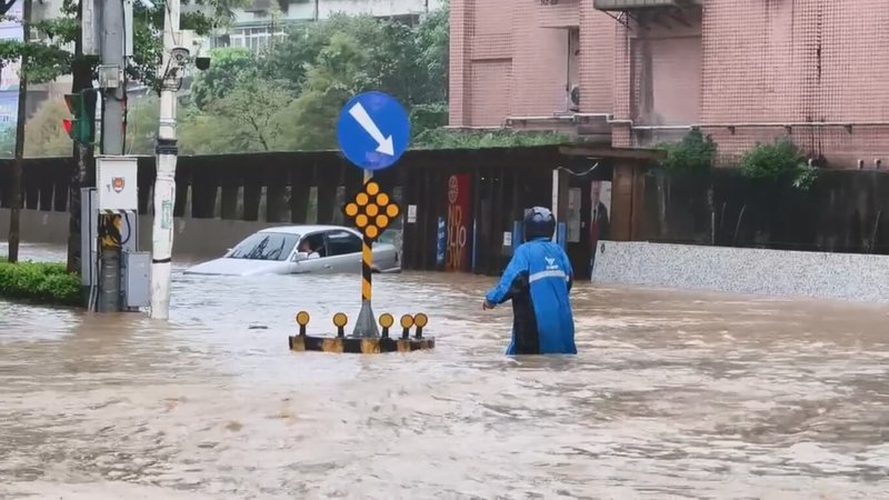 基隆市4日上午強降雨,導致大武崙溪溢流至基金一路沿線。一輛轎車冒險涉水卻拋錨,新崙里長林金龍(藍色雨衣)見狀上前協助,將年長駕駛攙扶至路旁。(新崙里長林金龍提供)中央社記者王朝鈺傳真 115年9月4日