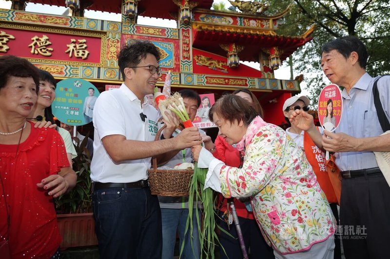 民進黨台北市長參選人沈伯洋（白衣）7日清晨前往台北南港區玉成公園掃街拜票，現場有民眾送上白蘿蔔與蒜苗象徵好彩頭。中央社記者翁睿坤攝　115年9月7日